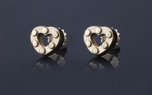 gold heart earrings with hexagonal studs on grey background