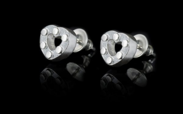pair of silver heart earrings on black background
