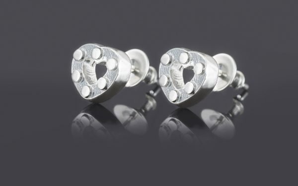 pair of silver heart earrings on grey background